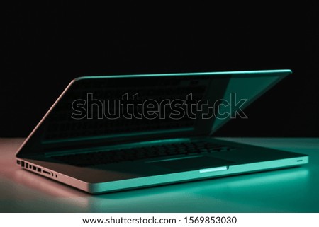Beautiful silver laptop in the color light on a table and night background.