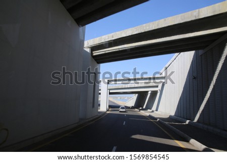 road tunnel under bridge at day . Concrete narrow underground tunnel for cars. Under the bridge is a pedestrian crossing.A small tunnel under the bridge on the road