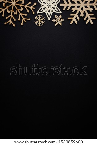 Black flat lay background for New Year  Christmas with hand made wooden snowflakes and empty space for text below.Handmade crafts for winter holidays shto from above on clear backdrop
