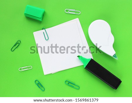Desk of a businessman in shades of green. Writing paper, paper clips and felt-tip pen.