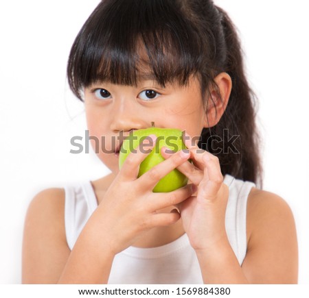 The picture of an Asian girl, long black hair, white skin, and black eyes. Age 7 years old eating a green apple in his hand is healthy and good for a white background.