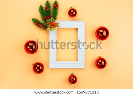 Christmas holidays composition, top view of red Christmas decorations and picture frame on yellow background with copy space for text. Flat lay, winter, postcard template, new year concept.
