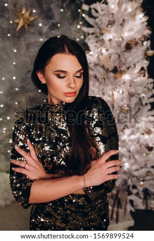 New Year photo session of a young girl. Portrait of a brunette by the New Year tree.

