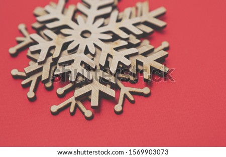 Wooden rustic snowflakes on red background for Christmas and Happy New Year poster design.Handmade crafts for winter holidays celebration party.Pile of hand made snow flake toys on paper backdrop