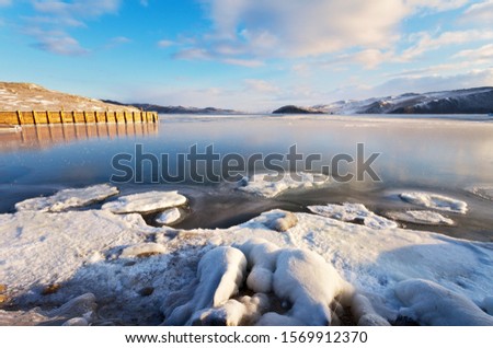 Baikal Lake in December morning. Ferry pier in the Olkhon Gate Strait at dawn (Olkhonskie Vorota). Beautiful winter landscape of a freezing lake. Change of seasons, natural background. Winter travel