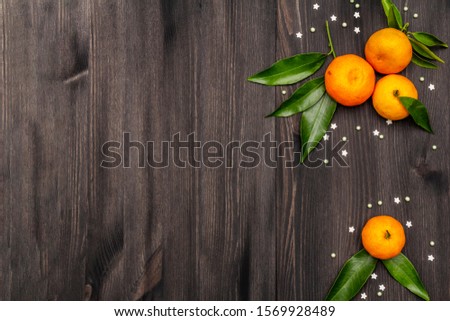 Fresh ripe tangerines with leaves and sprinkles. New Year or Christmas wooden background. Festive good mood concept, copy space, top view
