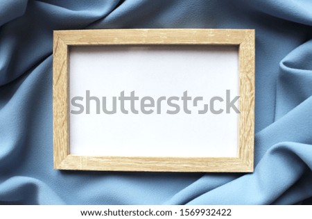 Photo frame on pale blue fabric background. Empty space for the inscription.