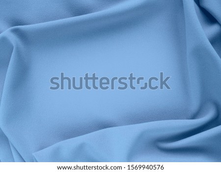 Gray-blue powdery abstract background of wavy silk. Fabric with pleats. Calm pastel colors. Satin, silk or satin creates a beautiful drape. Fashion design, background.