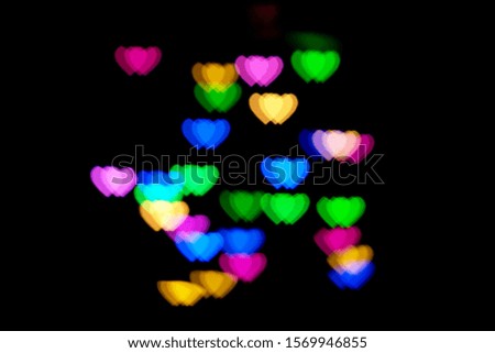 Multicolored hearts bokeh of blue and orange colores on black background. Texture for holidays