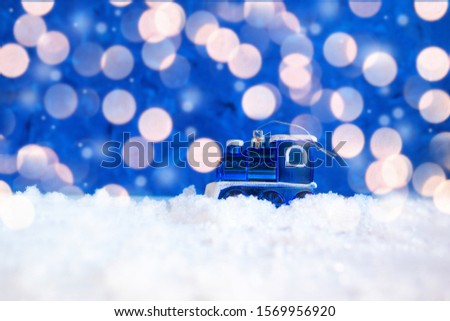 Christmas tree toy in the form of a train on a blue background with bokeh and snow. Free space for text