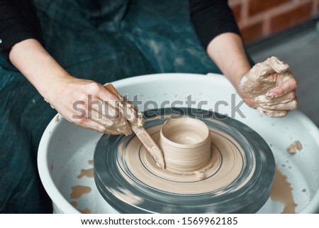 Woman making ceramic pottery on wheel, hands close-up, creation of ceramic ware. Handwork, craft, manual labor, buisness. Earn extra money, turning hobbies into cash and turning passion into a job Royalty-Free Stock Photo #1569962185