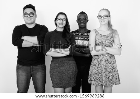 Studio shot of happy diverse group of multi ethnic friends smiling with arms crossed while wearing eyeglasses together