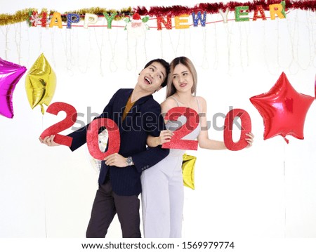 Young couple at a party holding red number of year 2020. Happy New Year celebration.