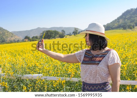 Attractive beautiful asian women having fun taking selfie self-portrait photo on flower field in Amphoe Tak Fa, Nakhon Sawan Province, Thailand. Holiday and travel vacation concept. 