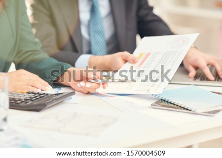Close up of unrecognizable businessmen pointing at documents during business meeting in office, copy space