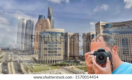 Portrait of a photographer covering her face with the camera taking shots of Abu Dhabi skyline, UAE
