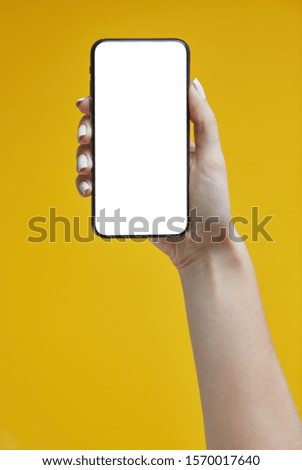 Woman hands holding smartphone on a yellow background. Smartphone mockup with white screen