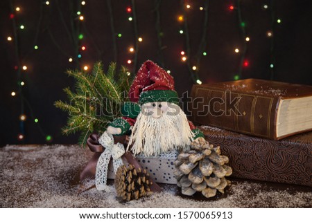 A beautiful Christmas background with a funny gnome sitting in an elegant box, next to pine cones, all covered with snow. Concept, holiday symbol, Christmas, New year