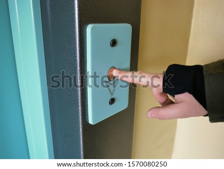 finger presses the Elevator call button close up