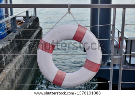 Red and White Life Preserver Ring, Lifebelt or Lifebuoy is hanging at Riverside