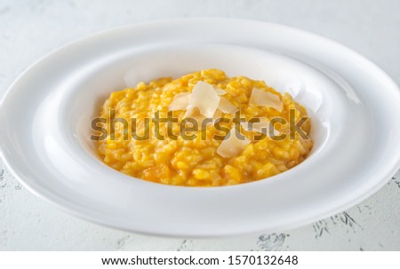 Portion of pumpkin risotto with slices of parmesan