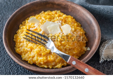Portion of pumpkin risotto decorated witn slices of parmesan