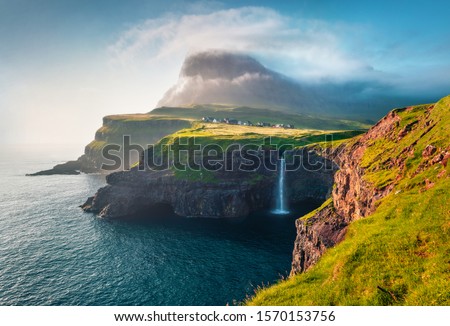 Gorgeous morning scene of Mulafossur Waterfall. Amazinf summer view of Vagar island, Faroe Islands, Denmark, Europe. Beauty of nature concept background. Royalty-Free Stock Photo #1570153756