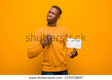 young african american black man against orange wall wholding a placard