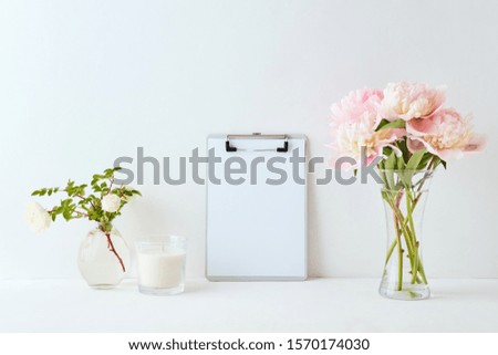 Mockup with a clipboard and pink peonies in a vase on a white background