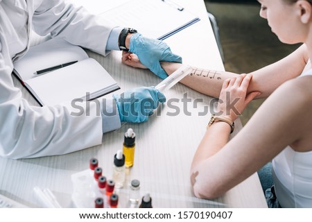 overhead view of allergist holding ruler near marked hand of woman  Royalty-Free Stock Photo #1570190407