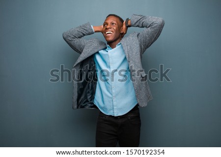 young african american black man smiling and feeling relaxed, satisfied and carefree, laughing positively and chilling against grunge wall