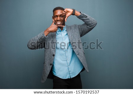 young african american black man feeling happy, friendly and positive, smiling and making a portrait or photo frame with hands