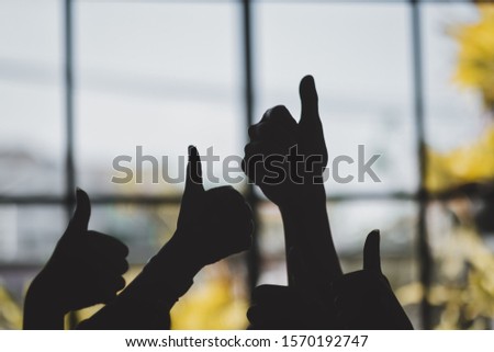 Silhouette image of many people's hands making thumb up sign