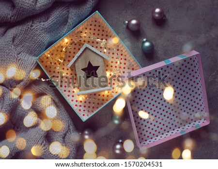 Wooden toy house with an asterisk in a gift box. Christmas background. The atmosphere of magic. Christmas decorations.