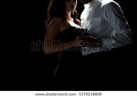 cropped view of bearded man standing with woman holding glass of red wine isolated on black 