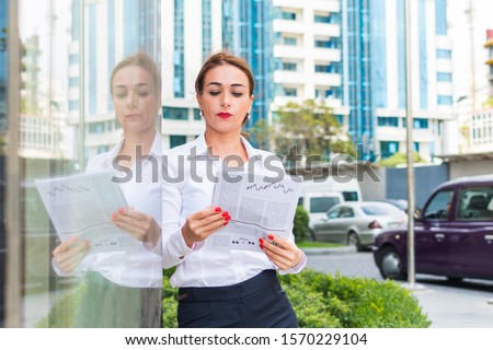 business woman reading a newspaper outdoors in the city