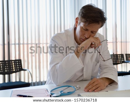 Tired doctor sitting at desk in doctor's office
