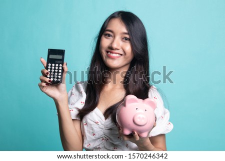 Asian woman with calculator and piggy bank on cyan color background