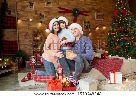 Mother and father with a child give gifts at Christmas