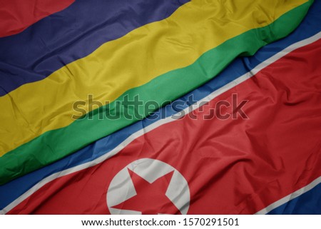 waving colorful flag of north korea and national flag of mauritius. macro