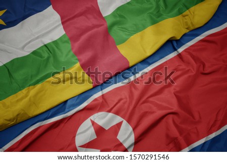 waving colorful flag of north korea and national flag of central african republic. macro
