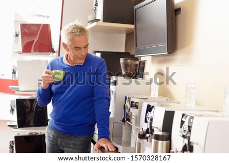A man looking at a selection of coffee makers in a shop