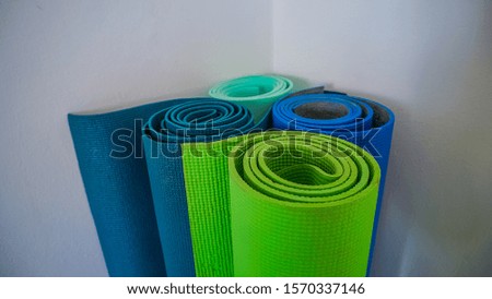  Different yoga mats stand twisted in the corner of the room, middle shot