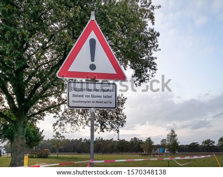 Sign with German text "Oak processionary, keep away from trees! Health hazard for humans and animals". The tiny toxic hairs of these caterpillars can trigger allergic reactions and skin irritation.