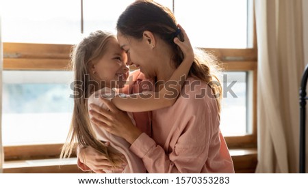 Affectionate sweet family young adult mom and small pretty cute daughter embracing bonding in sunny bedroom enjoying tender moments of foster care parent mother child love concept hugging at home