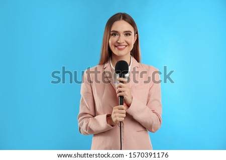 Young female journalist with microphone on blue background