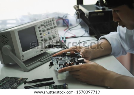 Close up of the hand men hold tool repairs electronics manufacturing Services, Manual Assembly Of Circuit Board Soldering.

