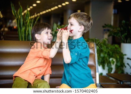Two young brother boy dreaming of becoming a pilot. A child with a toy airplane plays at airport waiting for departure on their aircraft. Travel and holidays with children concept.
