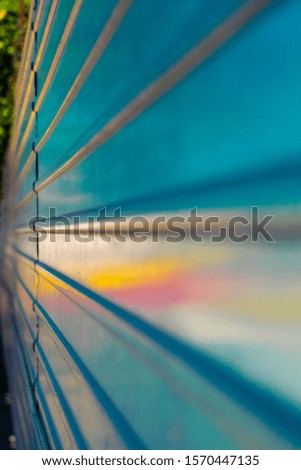 Metal fence with multi-colored reflection. Iron fence with colored highlights