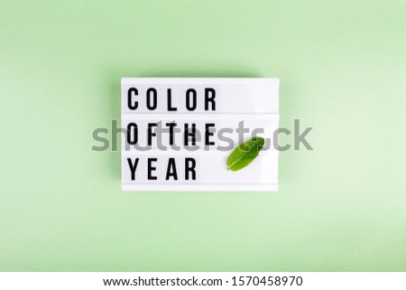 Retro lightbox with Color of the year wording and a mint leaf on the trendy solid green backdrop, place for text